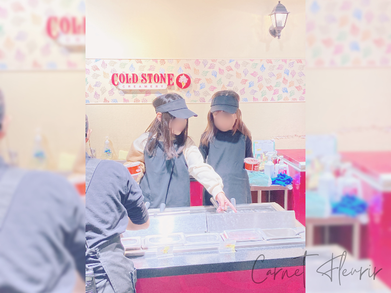 カンドゥーの職業体験でコールドストーンの制服を着てアイス作りに挑戦する子どもたち。ロゴ看板の前で真剣な表情が印象的。