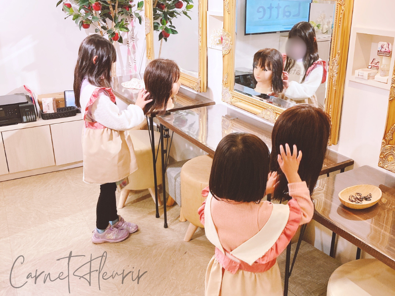 美容師体験中の子どもたちがマネキンの髪をスタイリングしている様子|カンドゥーのヘアサロン風ブースにて