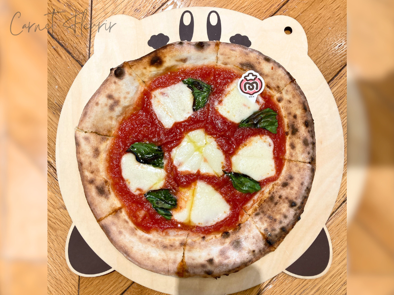 “マキシムトマトのマルゲリータピザ”の商品画像。カービィ型プレートに8カットの窯焼きピザが盛り付けられている
