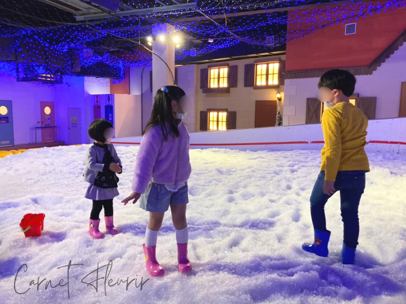 あそびマーレのスノーエリアで雪遊びを楽しむ子どもたち。ライトアップされた幻想的な空間で、ピンクの長靴が映える。
