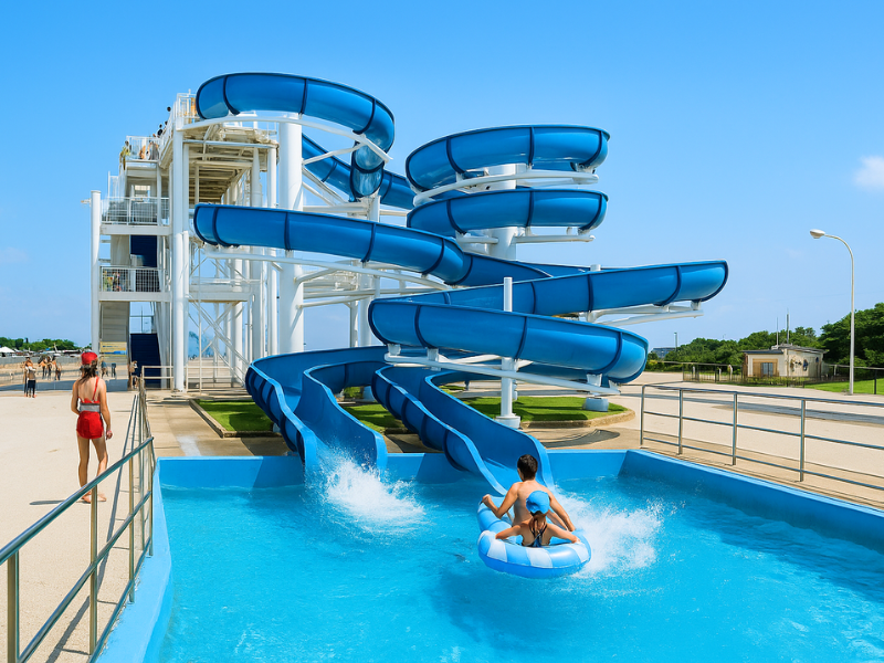 青い海と空に囲まれた大型すべり台つきのプール(富津公園ジャンボプールをイメージしたAI生成画像)