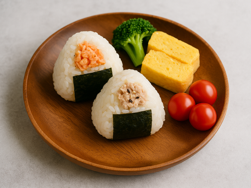 簡単ランチのワンプレート。おにぎり2つ、ブロッコリー、卵焼き、ミニトマトがのっている。