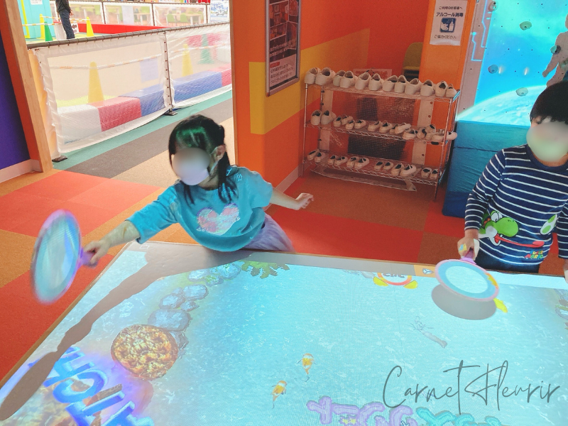 ファンタジーキッズリゾートでデジタル金魚すくい風のゲームに夢中な子どもたち