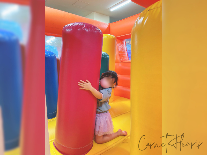 カラフルなエア遊具の中で柱にしがみつく子ども