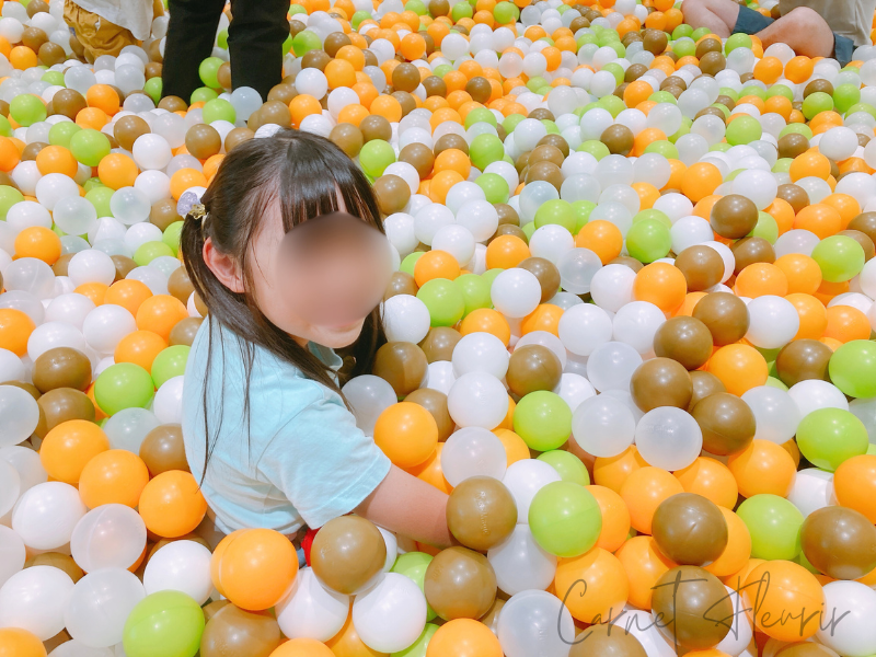約45,000個のカラーボールに囲まれ、嬉しそうに座っている女の子。