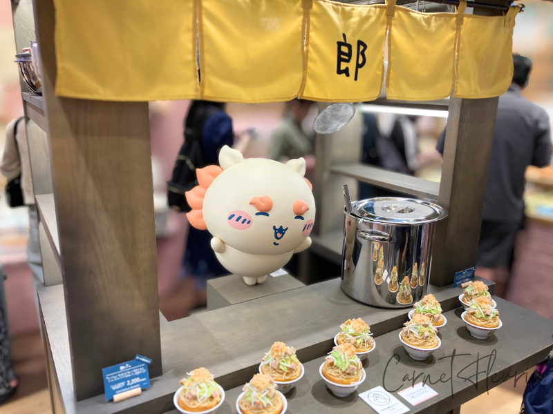 ちいかわベーカリーの店内にある郎ラーメン風屋台と、立っているシーサーちゃんの立体フィギュア