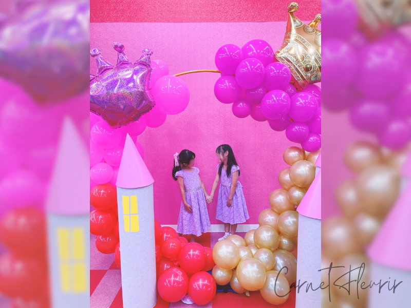 ファンタジーキッズリゾートのプリンセス撮影コーナーで、おそろいのラベンダードレスを着た女の子2人が手をつないで微笑み合っている様子