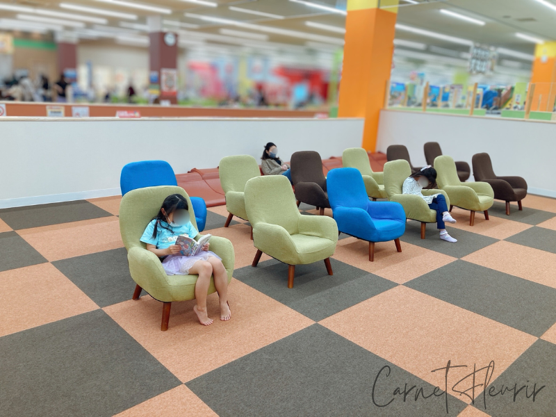 ファンタジーキッズリゾートの休憩スペースで本を読む子どもたちの様子。カラフルな椅子が並び、のんびり過ごせるエリア