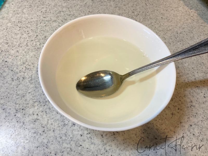 白い器にゼラチンを溶かした水が入っており、スプーンが添えられている。