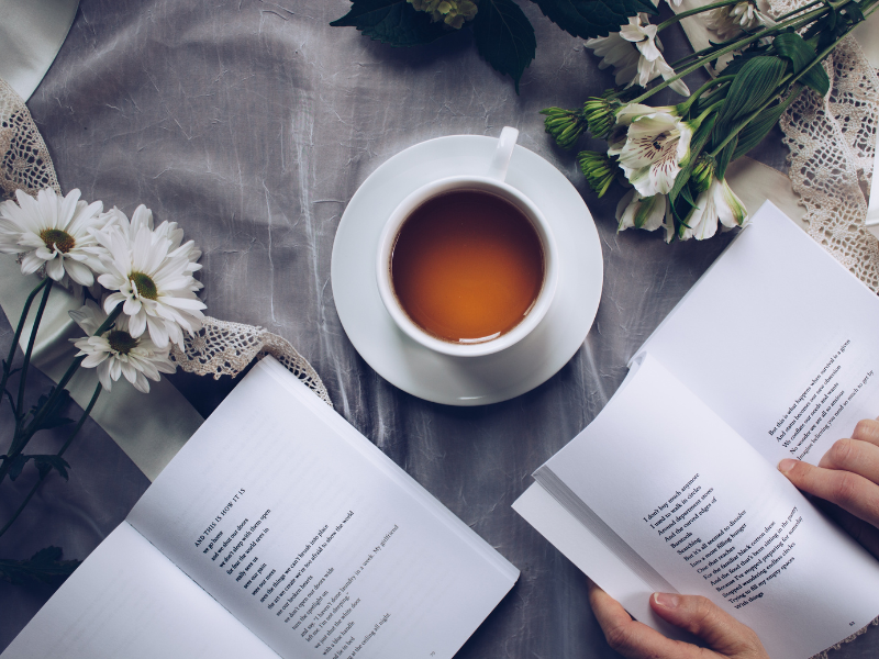 ティータイムを自宅で過ごすイメージ画像。ティーカップには紅茶、本を読みながら過ごしている。