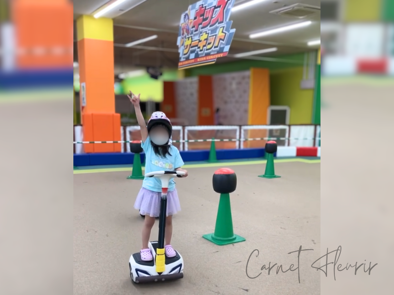 ファンタジーキッズリゾートのキッズサーキットで、スマートモビリティに乗ってポーズを決める女の子