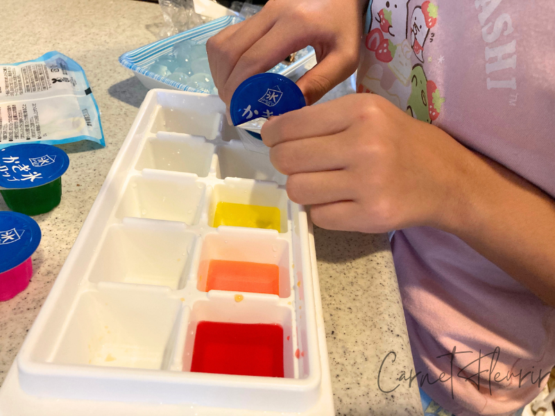 かき氷シロップを製氷皿に注いでいる子どもの手元