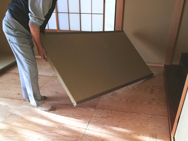 畳を持ち上げて運び出す作業中の様子