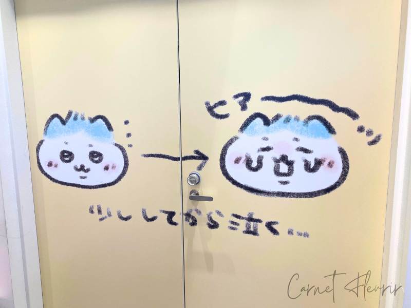 ドアに描かれたハチワレのベビーアート。泣き出す直前の表情が「少ししてから泣く…」という赤ちゃんあるあるを表現していて愛らしい。