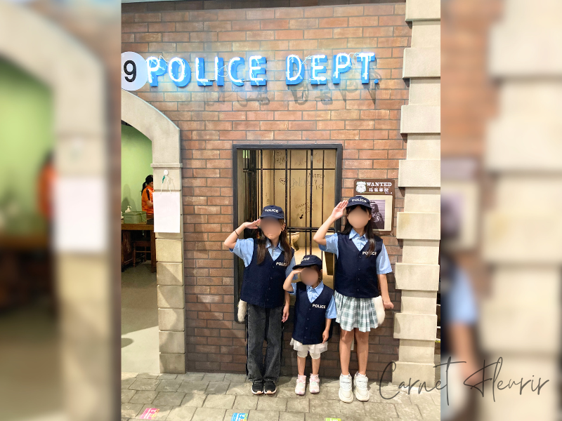 カンドゥー幕張の警察官体験。制服を着た子どもたちが警察署前で敬礼ポーズ