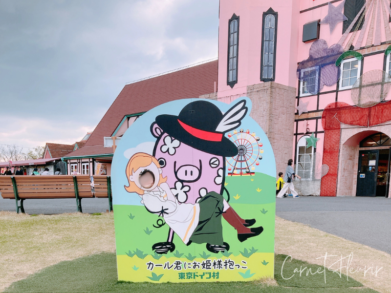 東京ドイツ村のマーケットエリアにある、カール君にお姫様抱っこされる顔出しパネル。背景にはメルヘンな建物。