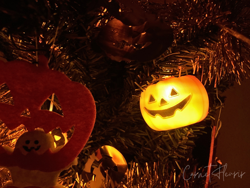 ハロウィンツリーに飾ったLEDライトが夜に点灯している様子。オレンジのかぼちゃライトが幻想的に光り、秋の夜を彩る。