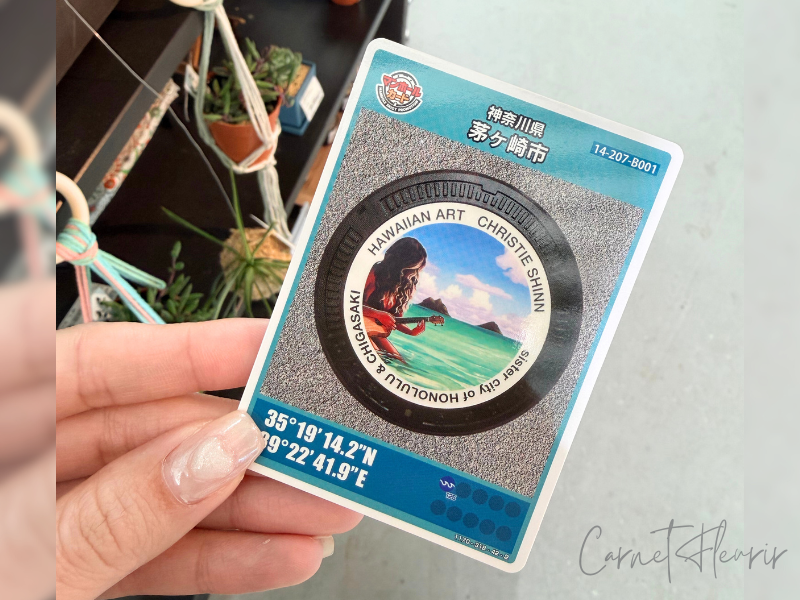湘南ちがさきにて配布されているマンホールカード(ハワイ拠点のアーティストであるクリスティ・シンのアートがプリント)
