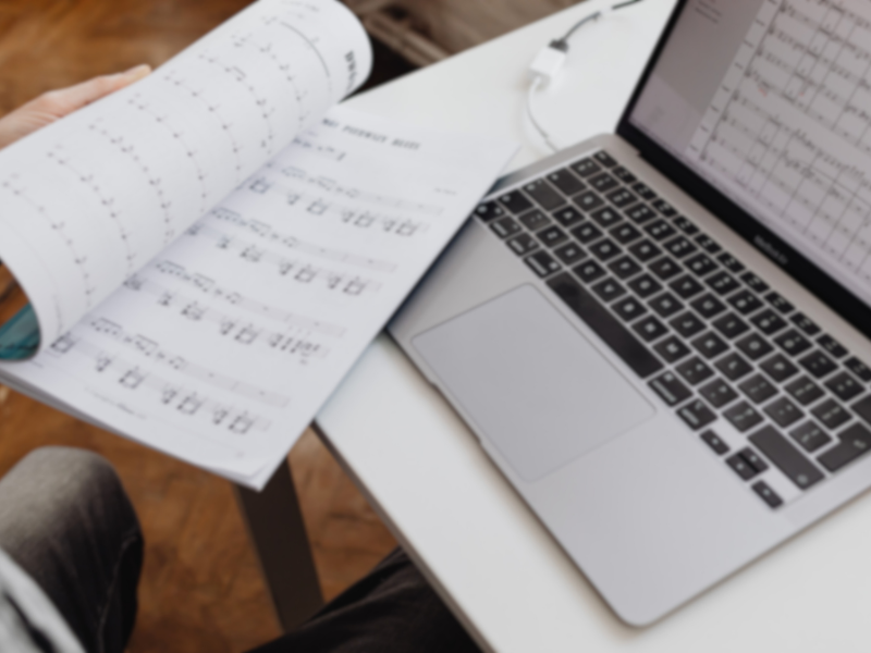 パソコンで楽譜を作成している様子。紙の楽譜とデジタル楽譜を見比べながら作業している