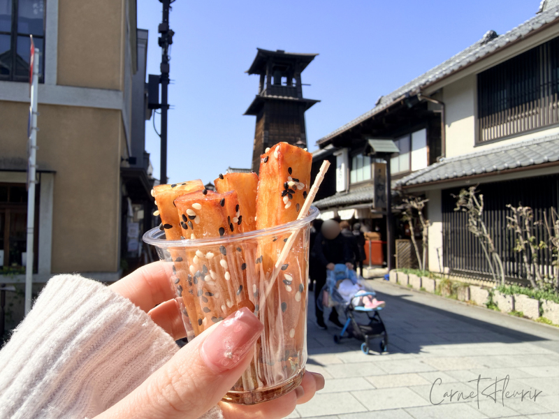 実際に購入したさつまいもスティック。背景には川越の時の鐘が写っている。