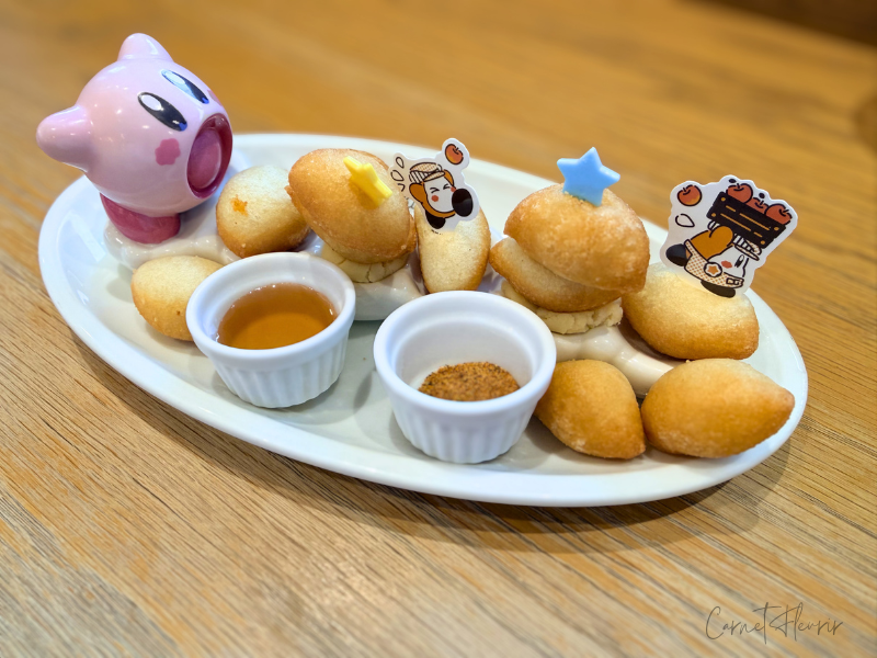 “ワドルディのころころ手ごねピッコラ”の商品画像。すいこみカービィから逃げるワドルディのピックがピッコラに刺さっている。